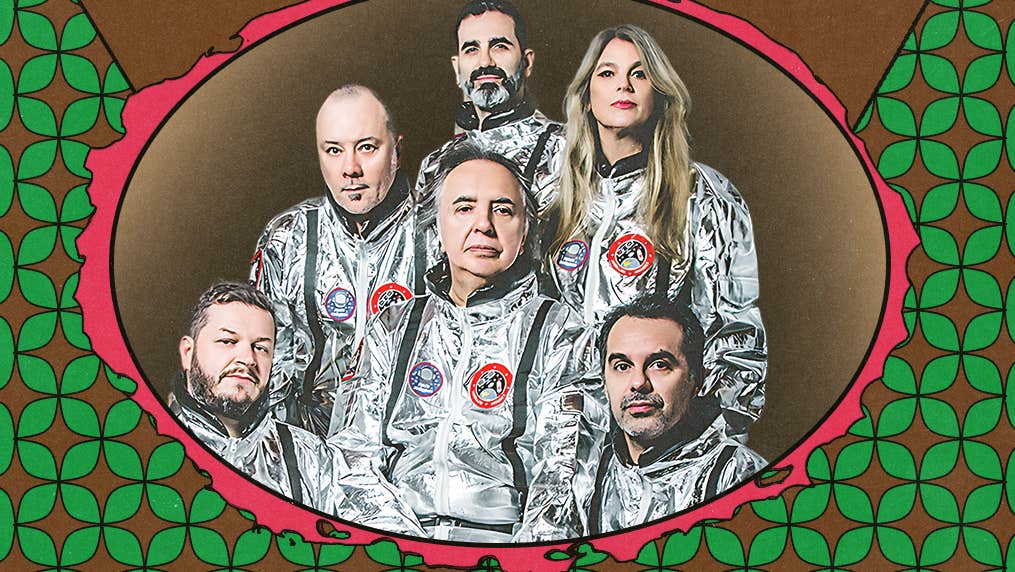 Group of 6 people in shiny silver space type suits looking proud.