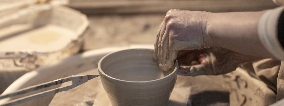 A close up of someone making pottery