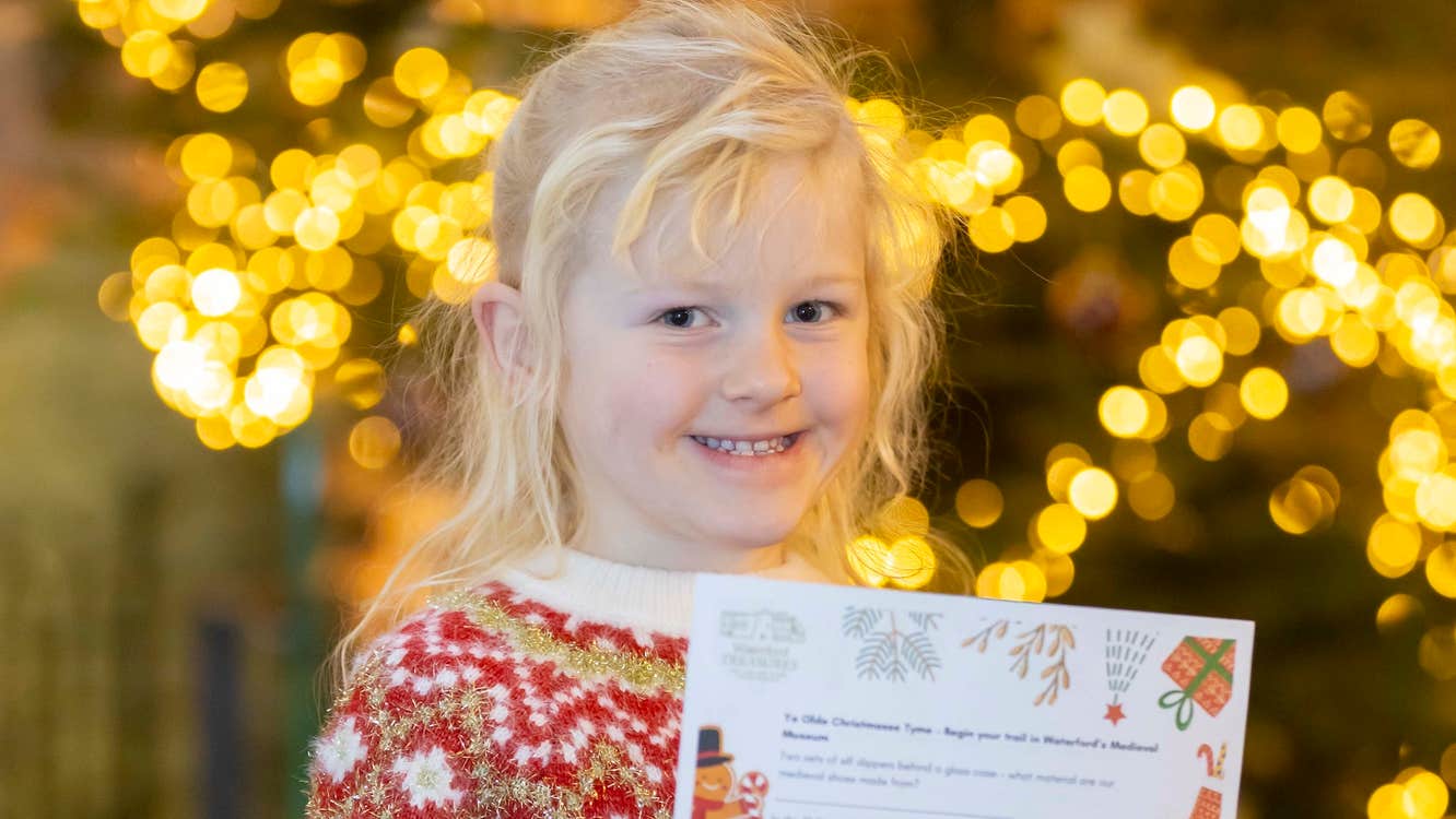 A smiling young girl holding up a piece of paper