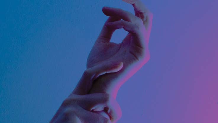 A pair of hands held up against plain blue, purple background.