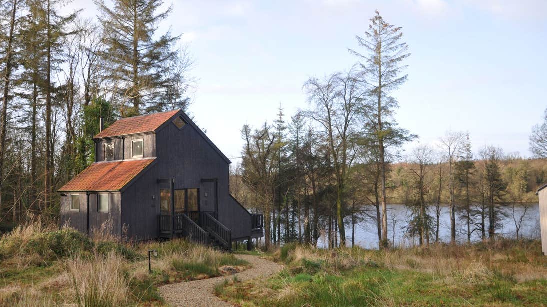 A wooden cabin beside a calm lake in Cavan