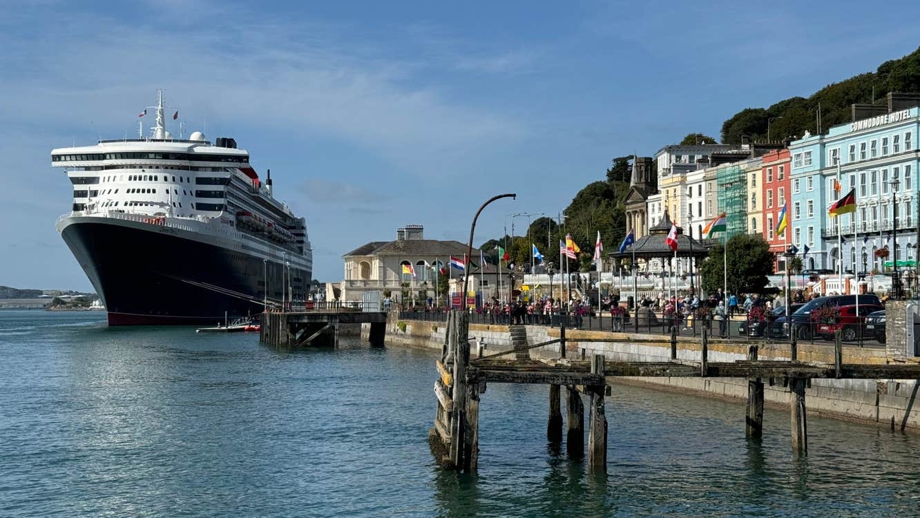 View of a large cruise ship docked at Cobh Cruise Port beside colourful waterfront buildings