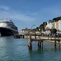 View of a large cruise ship docked at Cobh Cruise Port beside colourful waterfront buildings