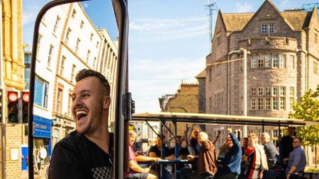 A pedal tour bike on a sunny city street with passengers chatting