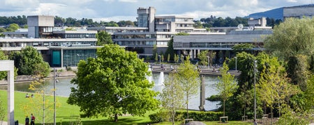 A view of the buildings at University College Dublin with trees and a pond in front