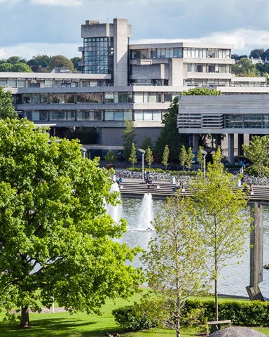 A view of the buildings at University College Dublin with trees and a pond in front