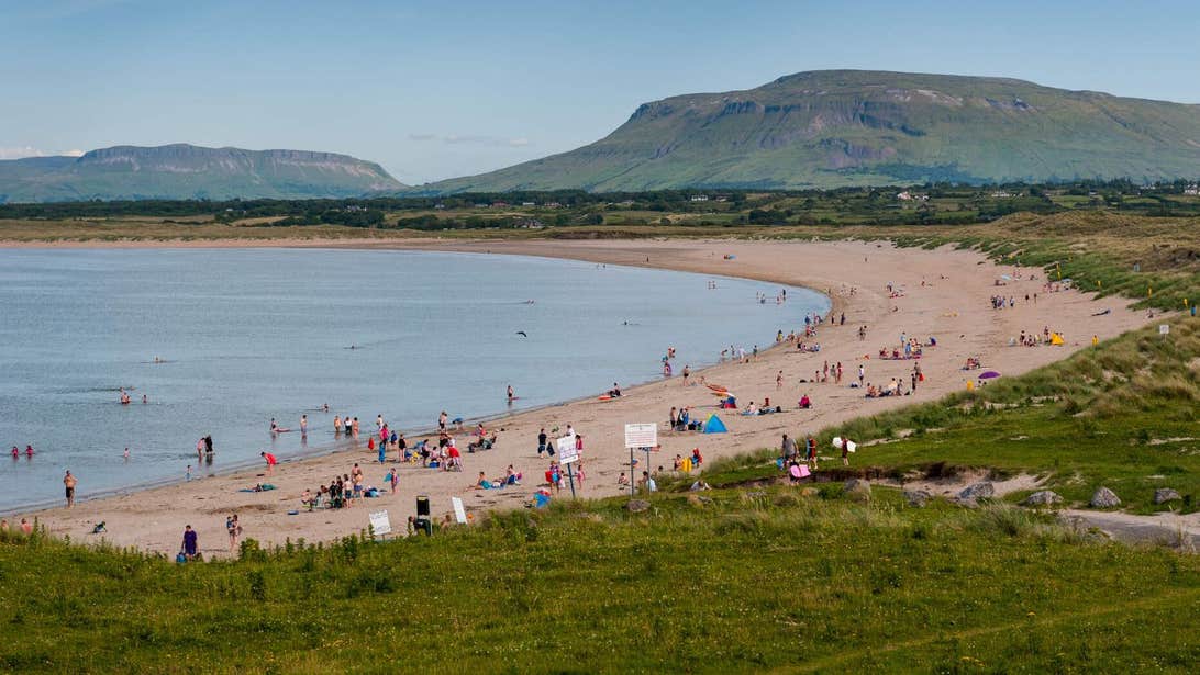 A view of Mullaghmore Beach in the summer with beach goers spread across the beach and in the water.