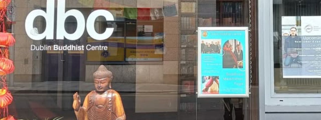 A window of a Buddhist centre with a Buddha in the window and a business logo
