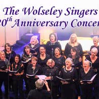 A choir of women holding song sheets, singing with a conductor at the front.