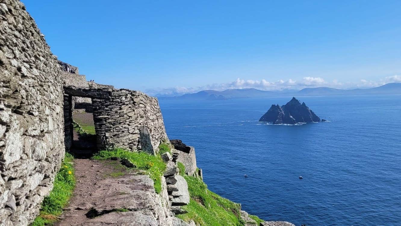 Stone and grass pathway on an island in the sea with another island in the background