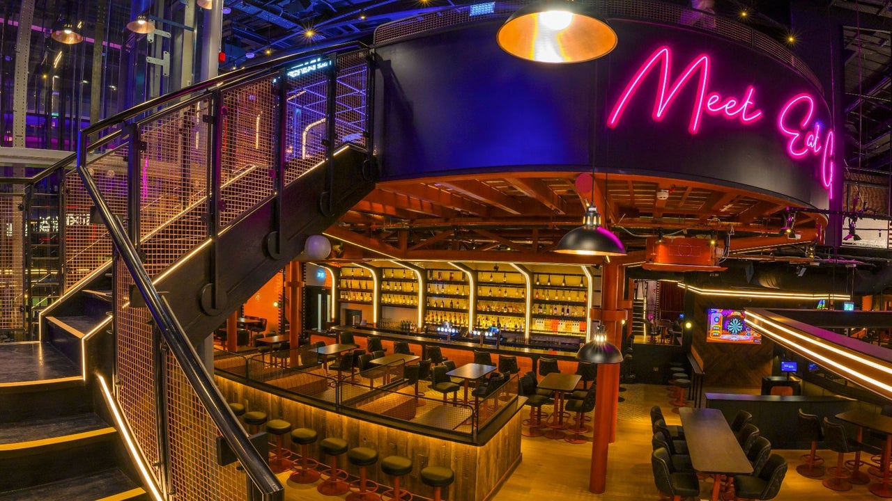 Bar area with neon lights over the counter and steps leading to an upstairs level