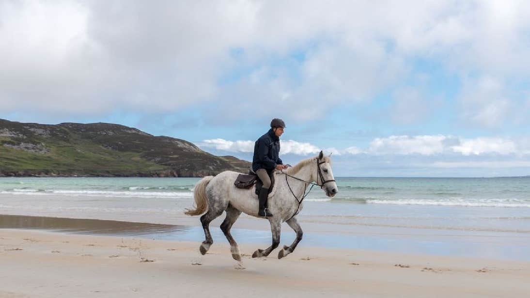 Person horse riding on the beach in County Donegal