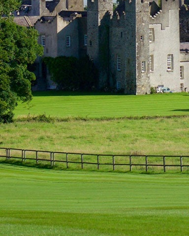 Golfers playing golf with a castle in the background