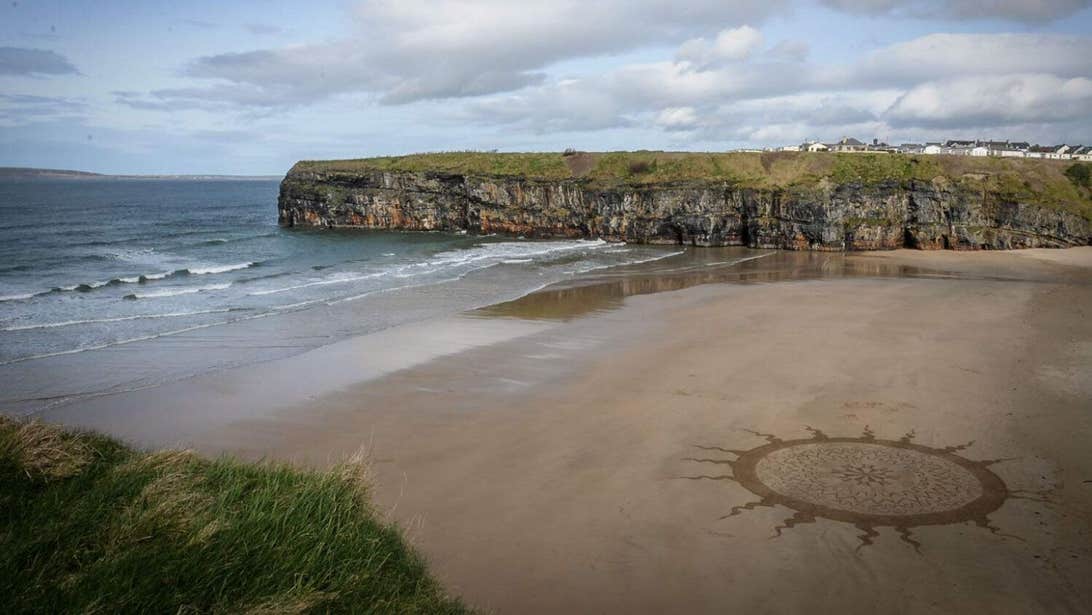 A big drawing of a sun in the sand at Ballybunion Beach in Kerry.