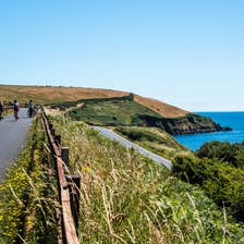 Three people cycling by the sea along the Waterford Greenway in County Waterford