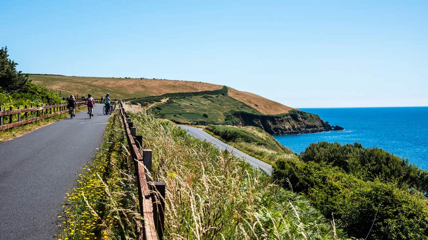 Three people cycling by the sea along the Waterford Greenway in County Waterford