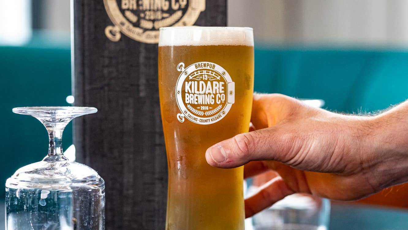 A pint glass of pale ale with the logo of Kildare Brewing Company on it