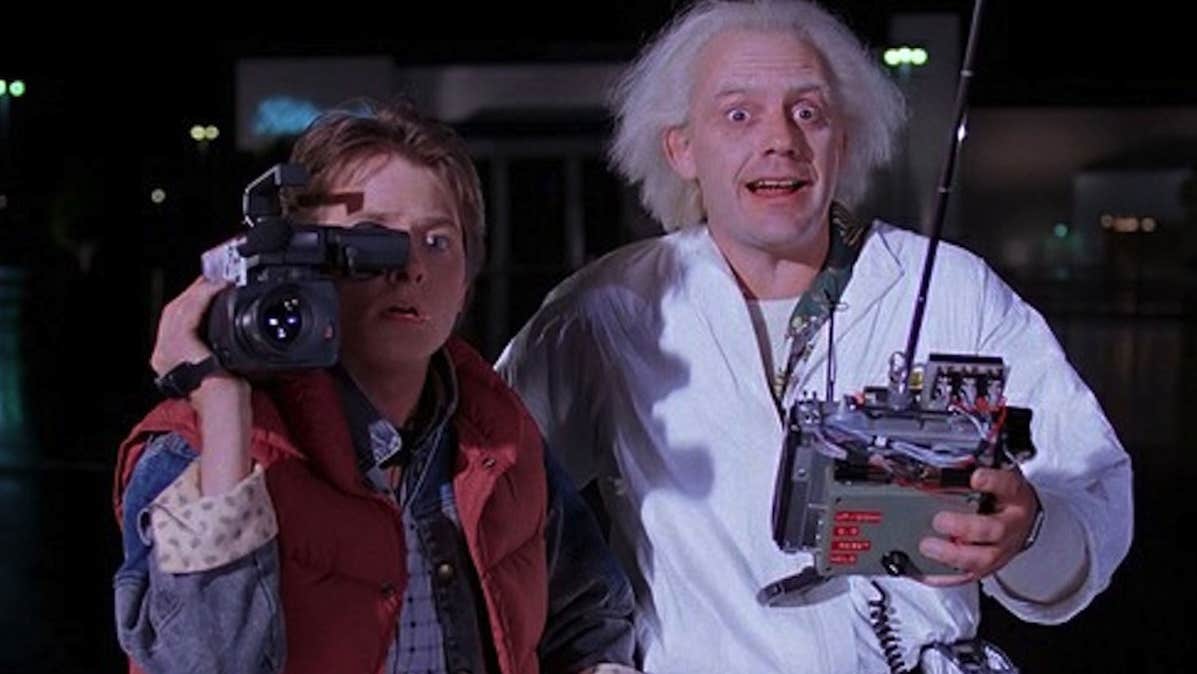 2 shocked looking men, one with a large video camera on one shoulder, the other holding a remote controller.
