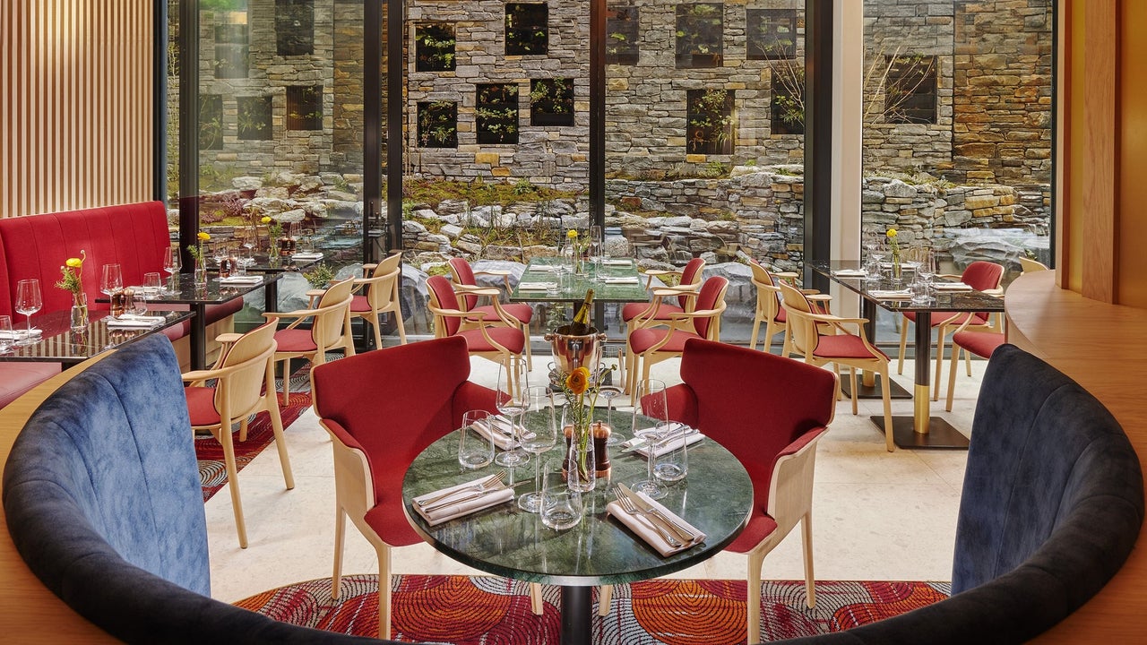 Cushioned booth with a round table set for service surrounded by more tables in a restaurant