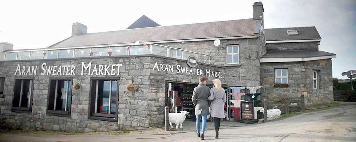 A couple walking arm in arm towards the entrance of the aran sweater market on Inis Mor Aran Islands