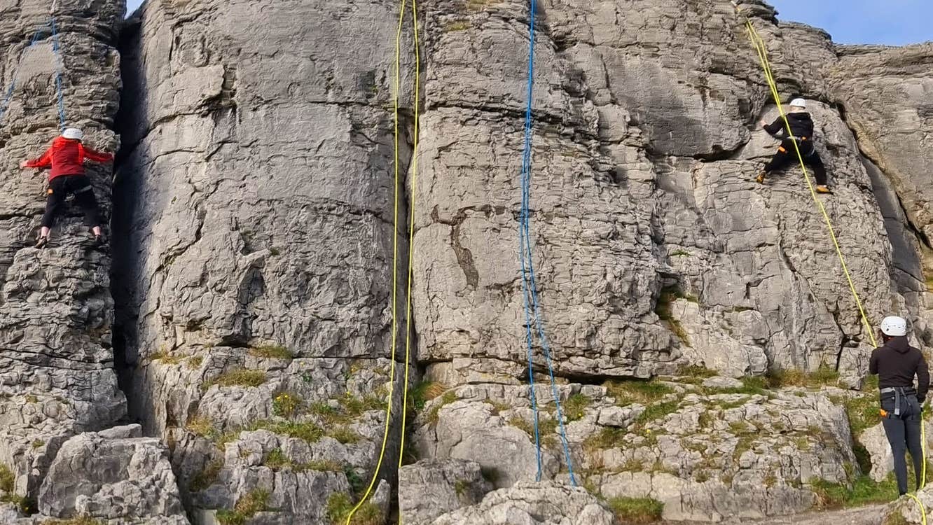People abseiling down a rock face with the Irish Mountaineering Academy