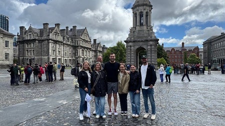 A small group of people posing in a courtyard at Trinity College in Dublin