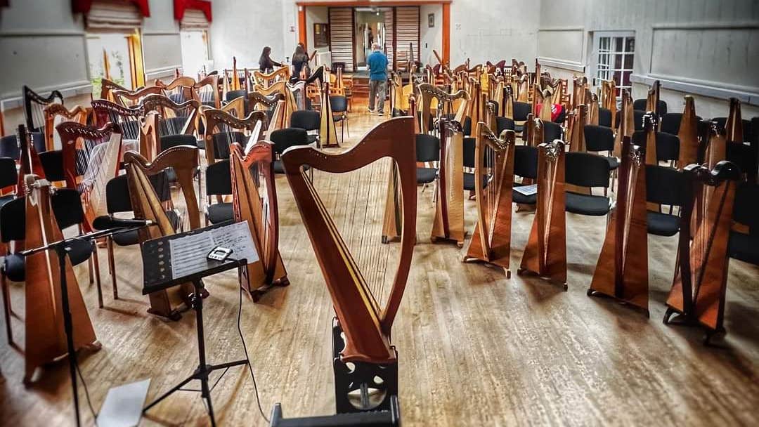 An empty hall of people with lines of harps in front of empty chairs