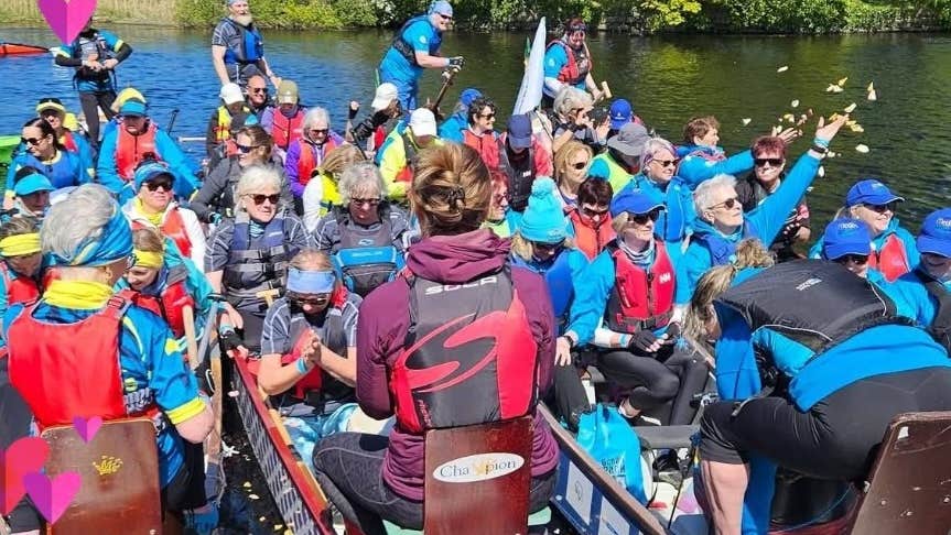 Groups of people in long canoe type boats all lined up tightly together on water. Flower Ceremony celebrating life, casting thousands of petals in the air in unison
