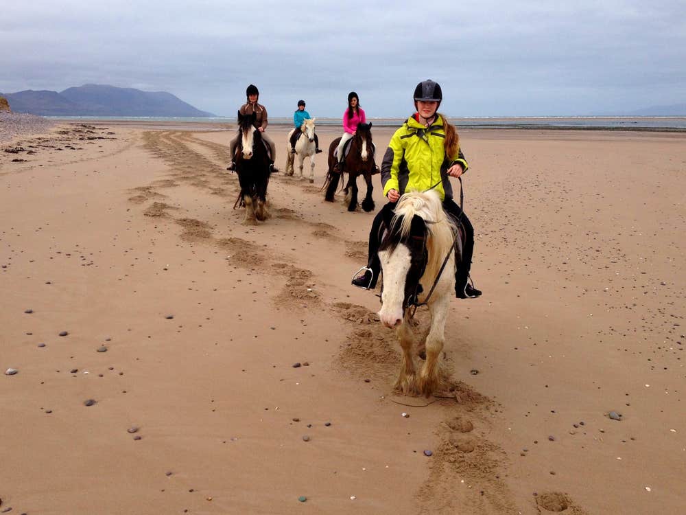 Four girls pony trekking along a sandy beach