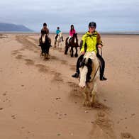 Four girls pony trekking along a sandy beach