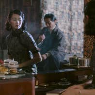 A woman is looking at a mirror. There is a man behind her.