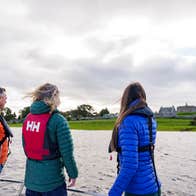 Three people looking out at Clonmacnoise monastic site from a river cruise.