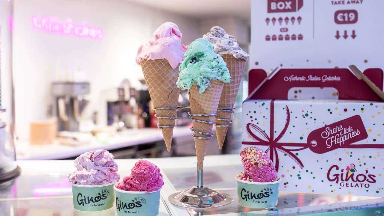 Colourful ice cream in cones and pots sitting on a shop counter