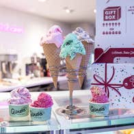 Colourful ice cream in cones and pots sitting on a shop counter