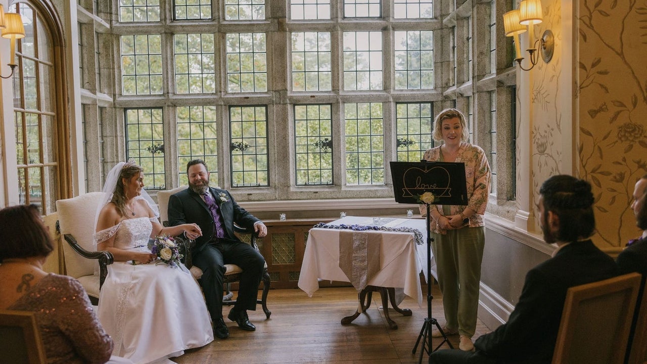 Bride and groom sitting as a celebrant speaks to seated guests