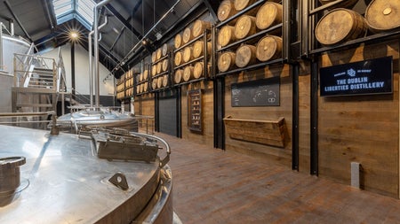 A room in a distillery with shelves lined with wooden whiskey barrels