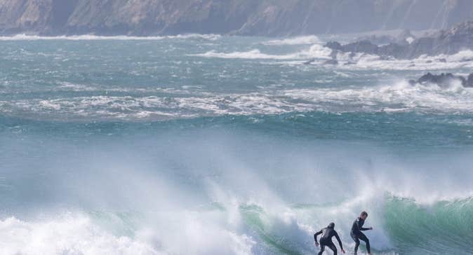 Two people surfing the big waves at Garrettstown