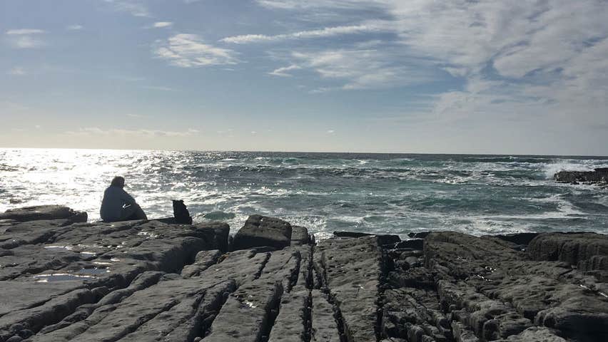 A person sitting on rocks looking out at the sea