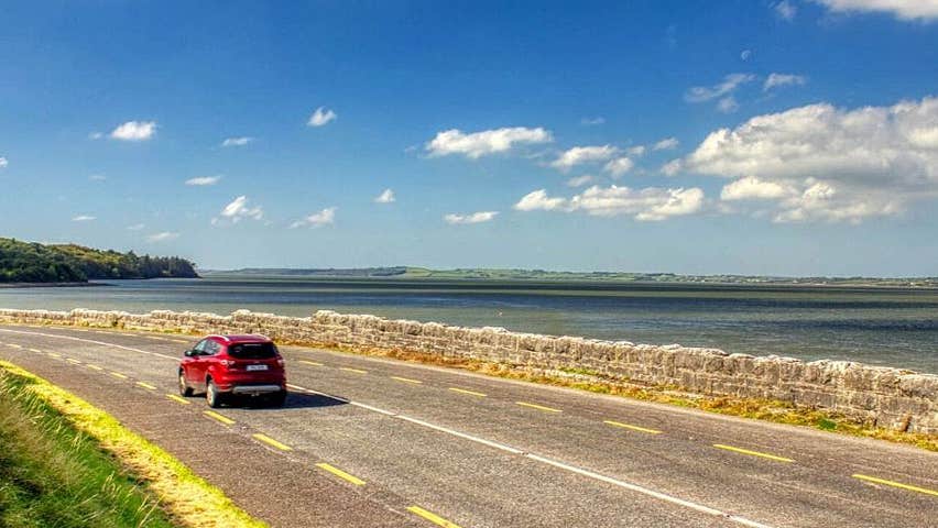 Shannon Estuary Way view of a car travelling on a road next to the estuary