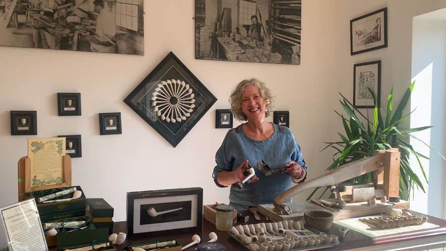 A large selection of clay pipes on display on the counter and the wall