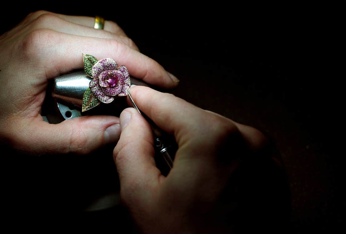 A flower shaped luxury piece of jewellery being worked on by hand
