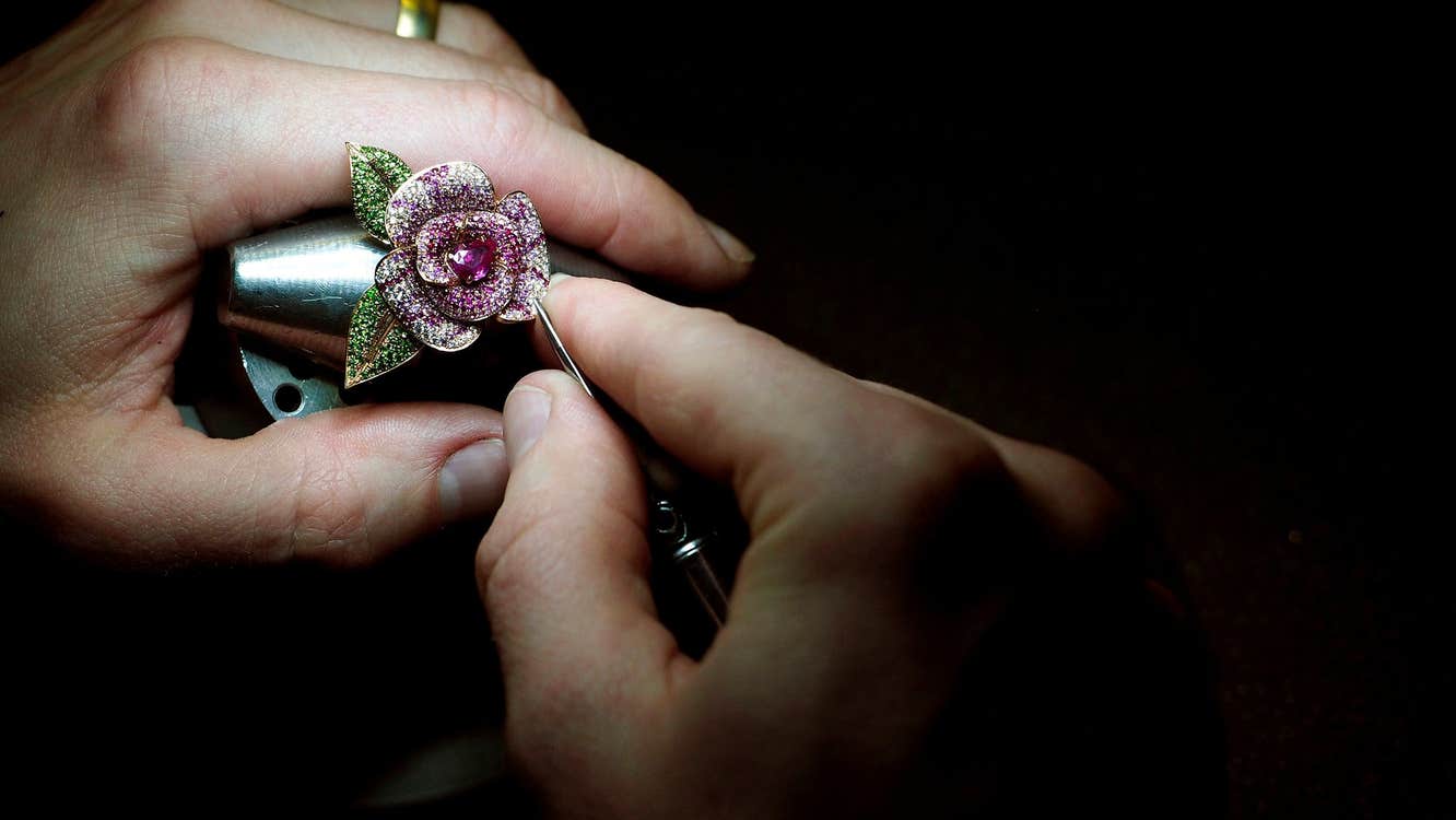 A flower shaped luxury piece of jewellery being worked on by hand