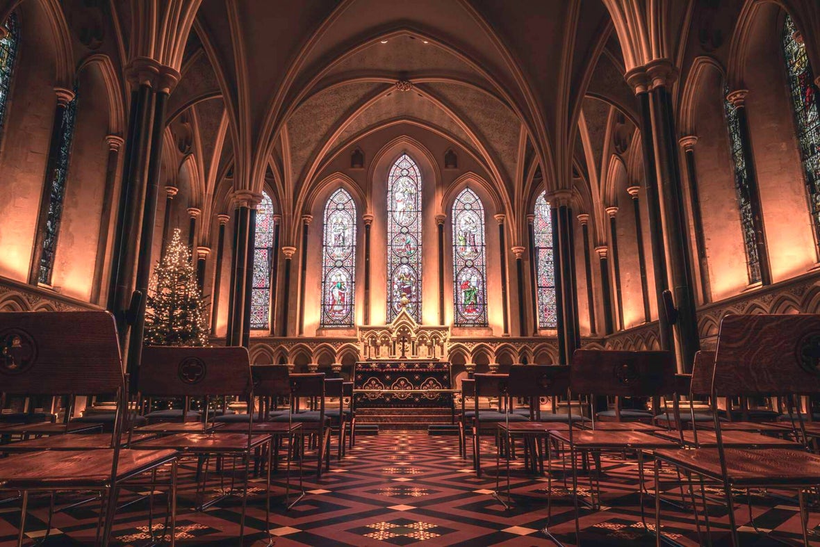 A view inside St Patrick's Cathedral with a Christmas tree near the altar and the church dimly lit with golden lights.