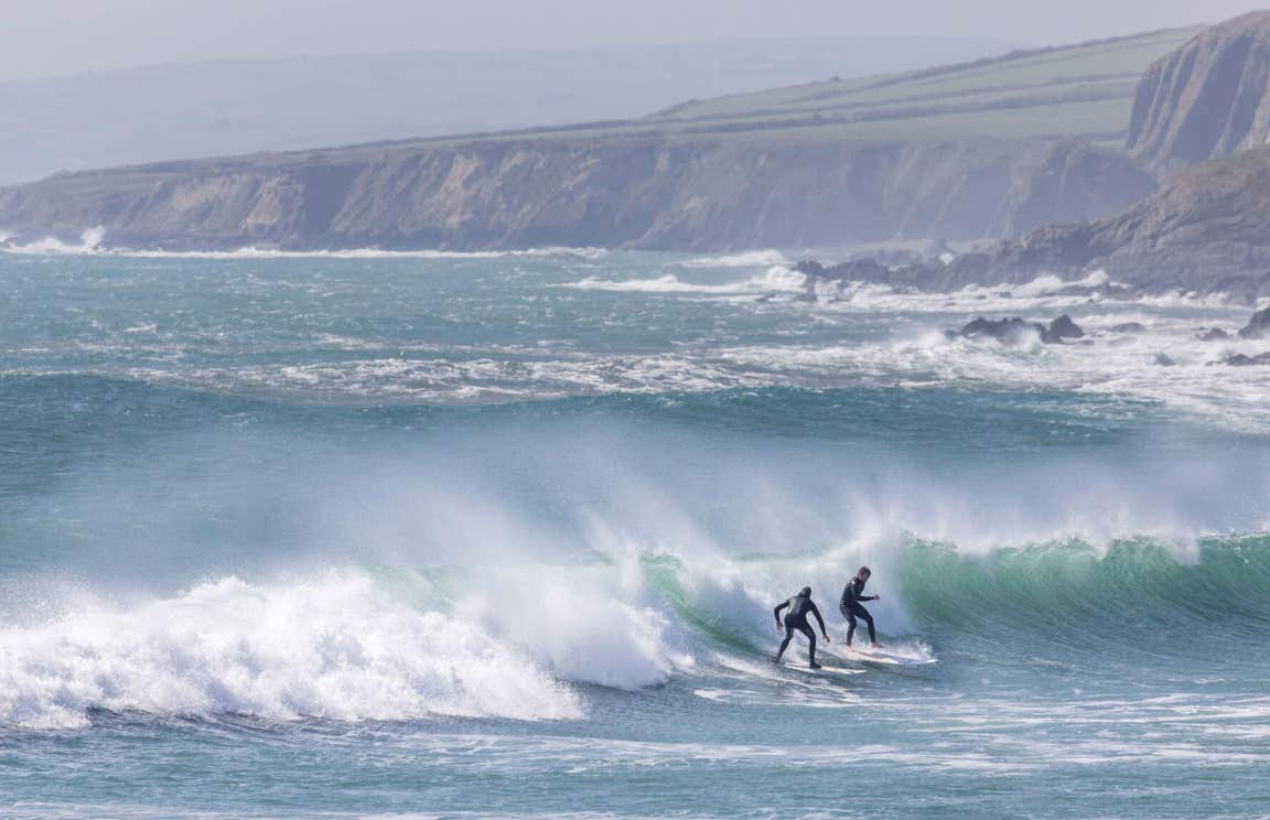 Two surfers on a wave at Garretstown Beach in Cork.