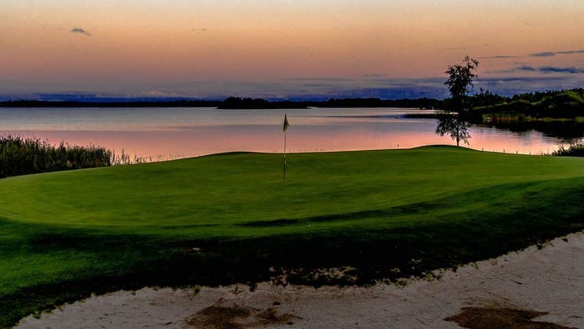 A golf course beside a lake at sunset
