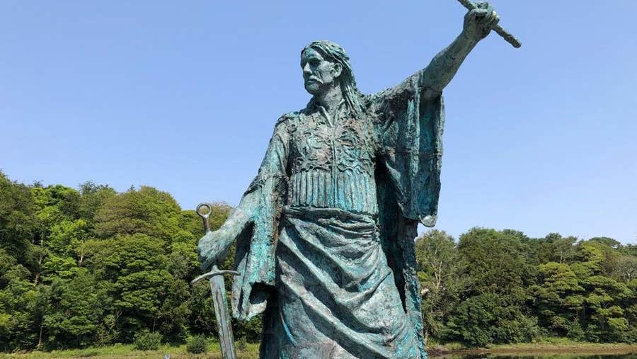 Sculpture of a man with arm outstretched and a sword in the other hand