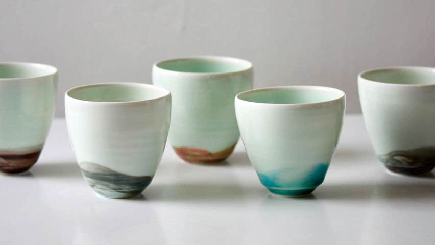 Five handcrafted espresso cups all white with different colours on the bottom of them