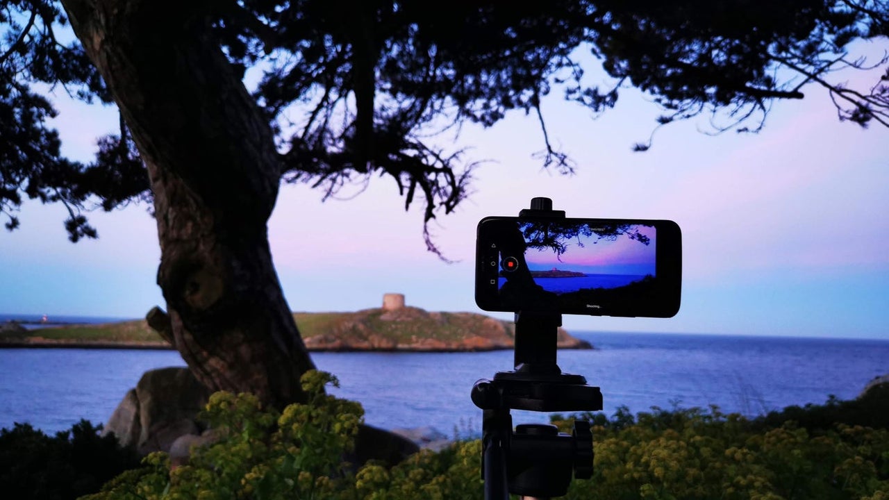 A mobile phone on a stand ready to take a sunset picture