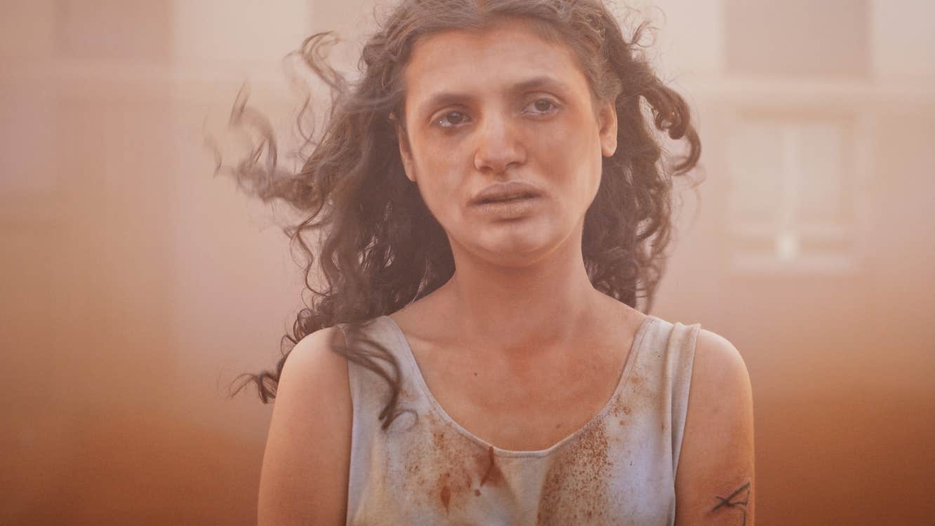 A disheveled young girl with an distraught expression, covered in dust.