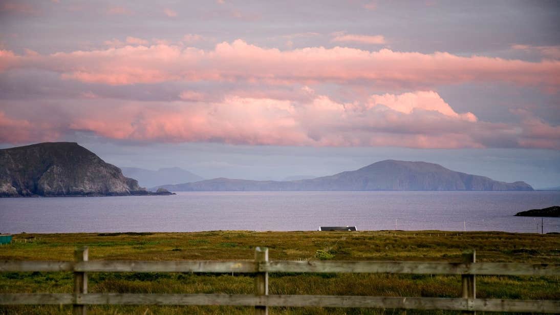 Looking out at a sunset across a field towards the ocean in Mayo on Achill Island